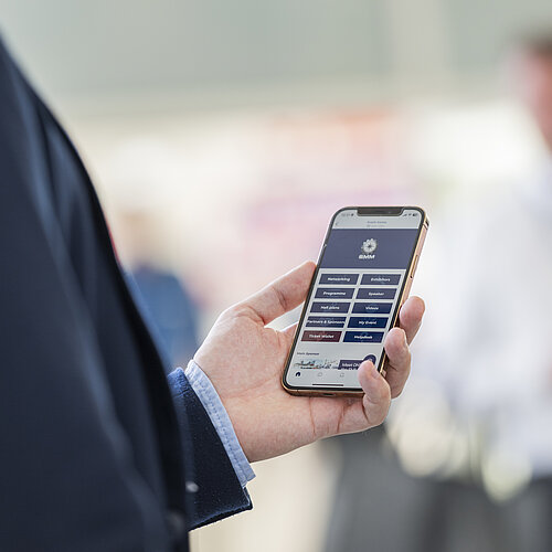 Nahaufnahme eines Menschen, der die SMM Networking-App auf einem Smartphone benutzt.