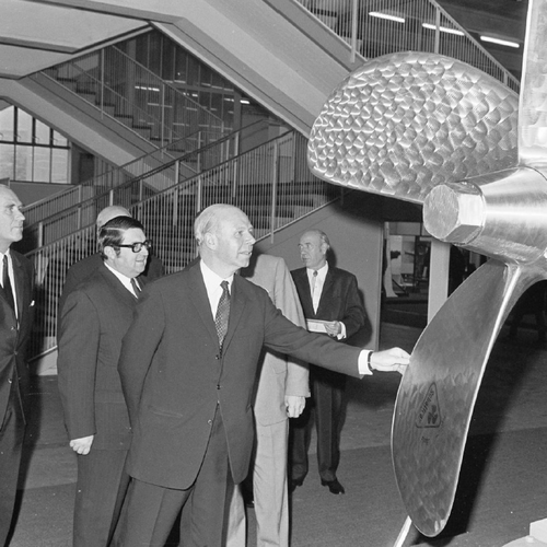 A group of men looking at a big turbine at a fair.