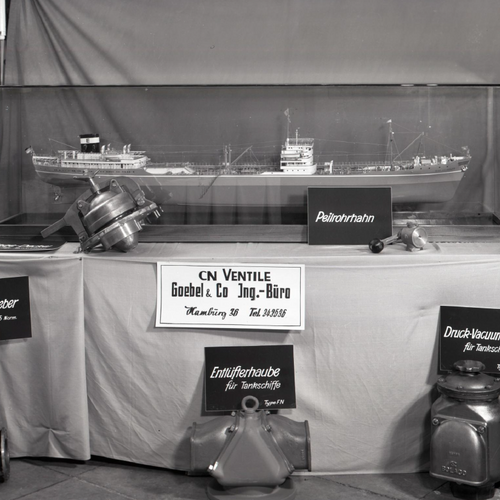 A historical picture of a Table with a miniature ship and multiple small ship parts from CN Ventile Goebel & Co.