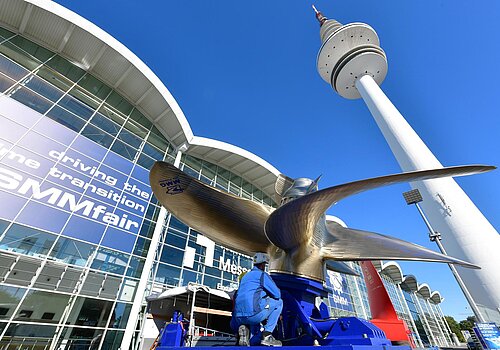 A golden wind turbine, which is getting installed in front of the Hamburg Messe building.