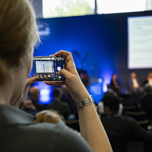 Person macht mit ihrem Handy ein Foto von der Bühne.
