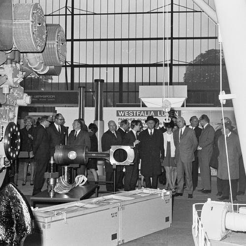 Historical picture of a group of trade fair visitors looking at large parts of a ship, which are in the foreground.