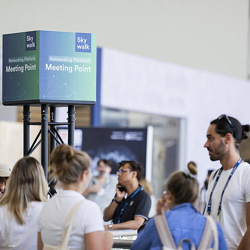 Ein Meeting Point der Hamburg Messe auf einer Veranstaltung ist zu sehen, umgeben von einigen Besuchenden.