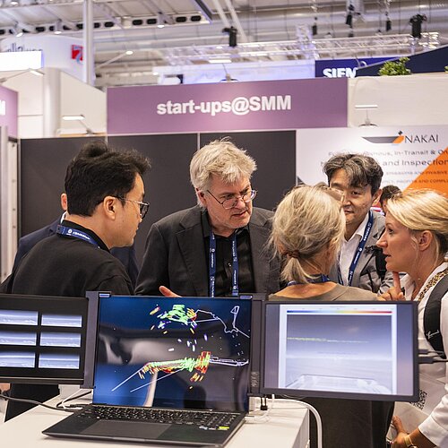 Ausstellende und Besucher unterhalten sich im Start-up Bereich. Es sind einige Bildschirme zu sehen. 