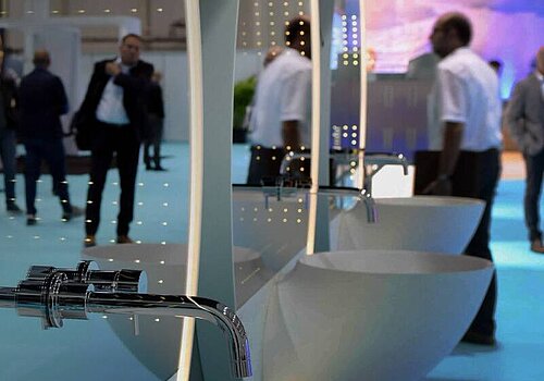 Multiple sinks with mirrors reflecting the fair visitors.